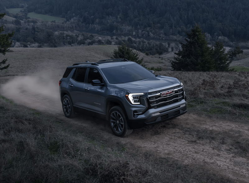 2027 GMC Terrain AWD driving on a rugged dirt trail through a scenic countryside landscape.
