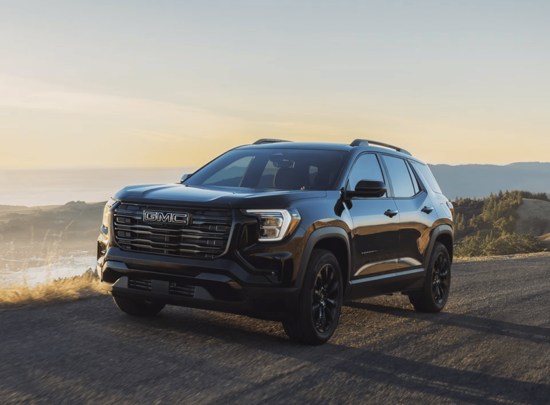 2027 GMC Terrain AWD driving on a scenic road at sunset, showcasing the SUV lineup's stylish exterior.